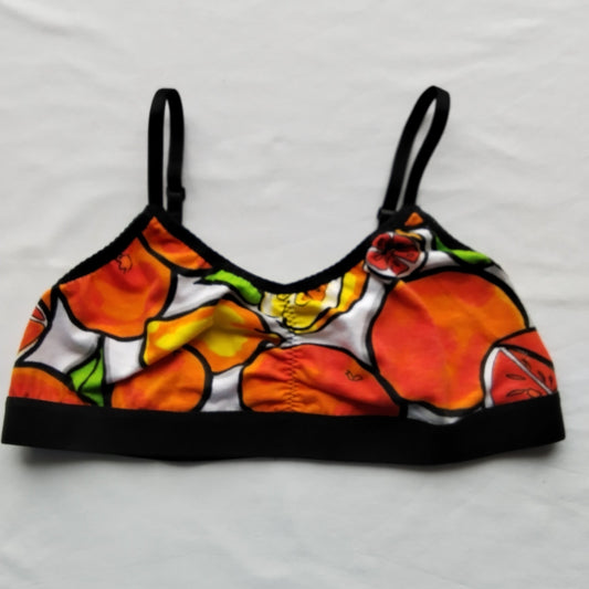 Brassière légère Taille L à plat – motif Vitaminée, grands agrumes orange et jaune style BD sur fond blanc upcyclé, bretelles et bande élastique noires, création artisanale Grosse Patate Création